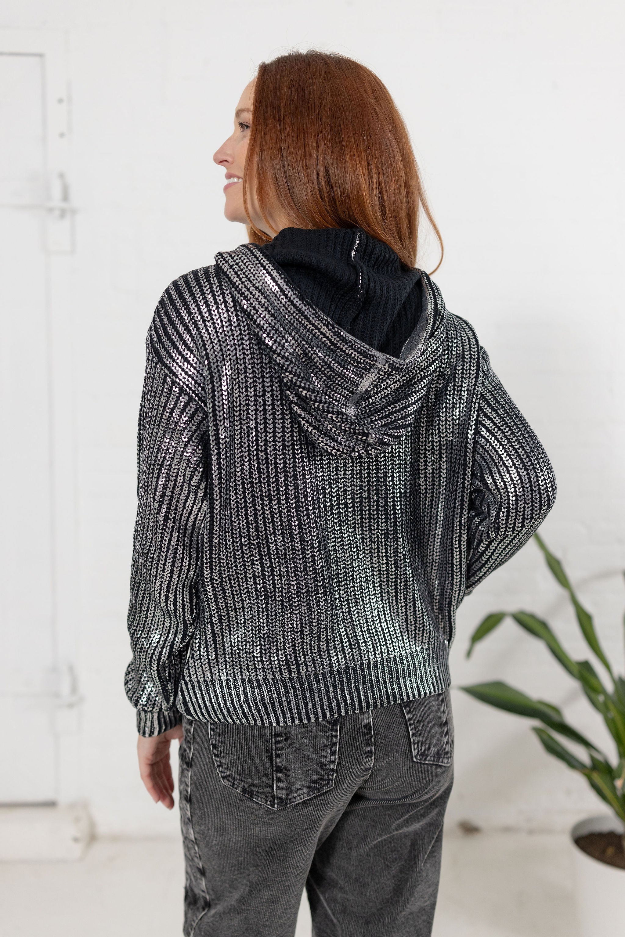 Model showing the back of the metallic knit sweater in silver from Mainstream Boutique Bloomington