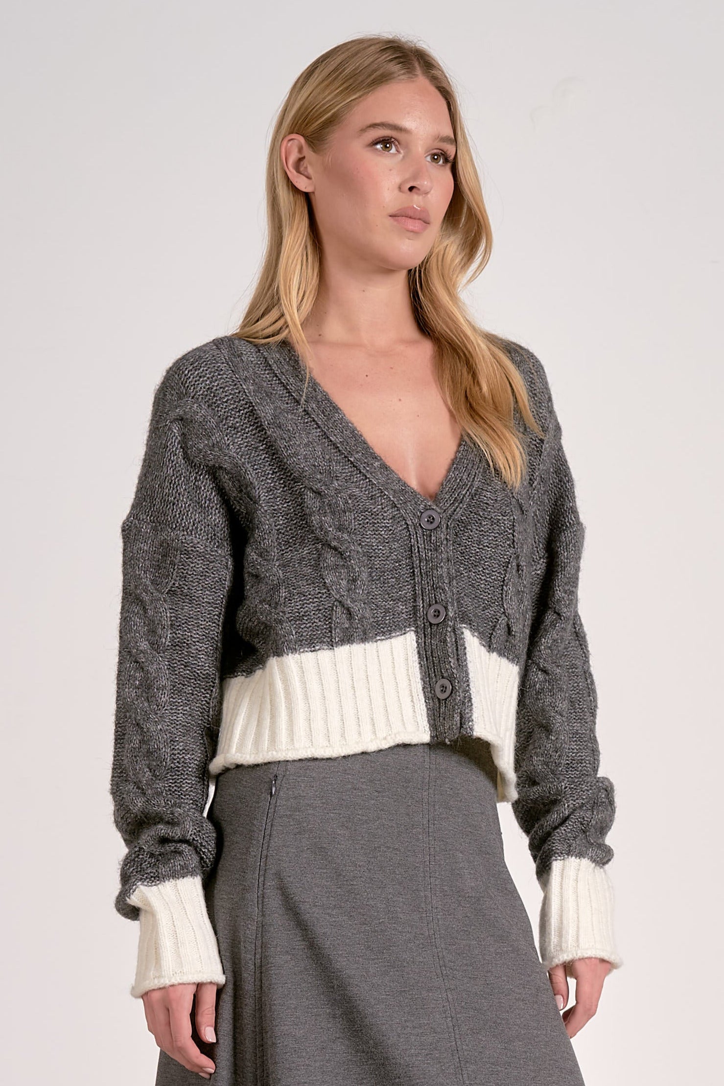 Side view of the grey and white two-tone cropped v-neck cardigan with cable knit and button front