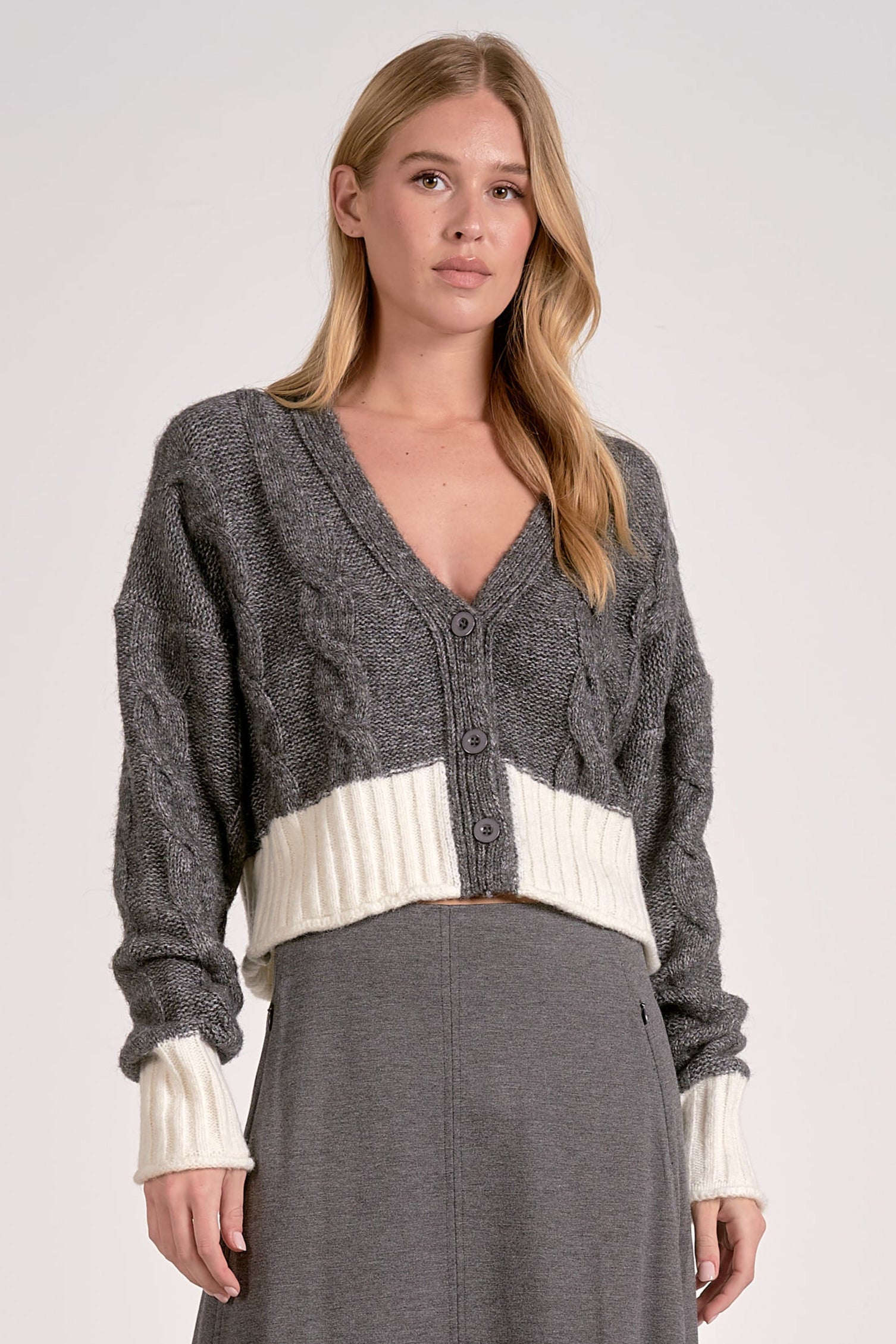 Front view of the grey and white two-tone cropped v-neck cardigan with cable knit and button front