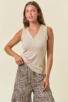 Woman wearing a beige sleeveless top and leopard print pants on a beige background