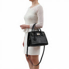 woman holding the black virginia satchel by the arm handles